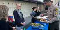 A catered meal at OC Sheriff, Compton Station served by Morale Booster volunteers, a Deputy filling his plate.