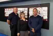 Diane Langan standing with a volunteer and the Captain of LAPD 77th Street Station, Behind them are decorated boards containing Thank You cards for the officers.