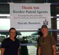 Morale Boosters President, Tom Langan and volunteer Mike Hagan, stand in front of a Thank You banner  at the El Centro Border Patrol station.