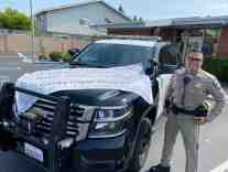 California Highway Patrol officer with an appreciation banner lying on the top of his patrol unit.