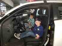 Brandon and Wyatt Cavanee sitting in a squad car during their tour of the station.  This is after a Morale Boosters event.